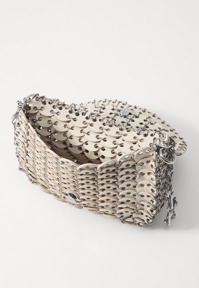 Balta, austītas ādas rokassoma ar metāla acīm un ķēdes akcentiem. Apaļa forma ar atvērtu augšpusi un teksturētu virsmu.