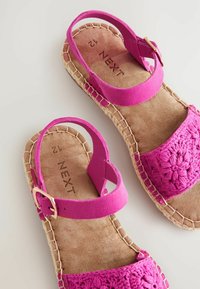 Rosa sandaler med virkade detaljer, suéde-liknande remmar och sula av jute. Har en spänne-stängning och en vadderad innersula för komfort.