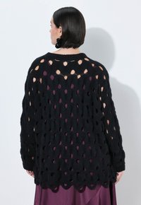 Zwarte gebreide cardigan met een open, golvend patroon en een geschulpt zoom. Het ontwerp heeft een losse pasvorm en lange mouwen.