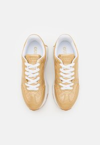 Sneaker in pelle dorata con lacci bianchi, caratterizzate da accenti testurizzati e un logo sulla linguetta. Punta arrotondata e suola ammortizzata.