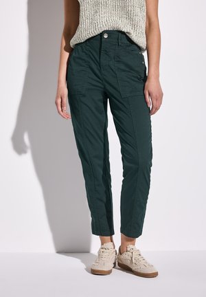 Dark green, tapered cargo pants with snap and button closures, side pockets, and a lightweight fabric texture, paired with beige sneakers.