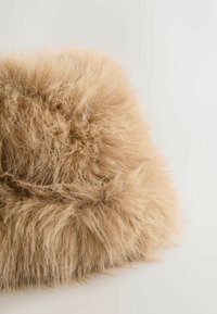 Fluffy beige fur fabric with long, soft fibers; irregular texture and rounded edges create a plush appearance. Suitable for decorative use.