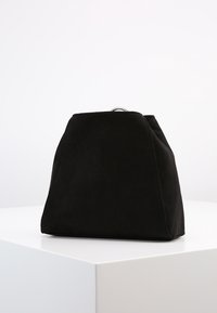 Svart mockaväska med en strukturerad, triangulär form och en silverdetalj högst upp. Slät textur utan synliga mönster.