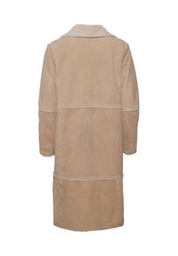 Beige shearling-takki, jossa on kaulus, pitkät hihat ja suora leikkaus. Näkyvät ompeleet ja saumat luovat tekstuurikkaan ilmeen.