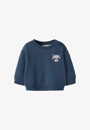 Navyblauer Pullover aus weichem Stoff mit rundem Halsausschnitt, im Oversized-Stil mit abgesenkten Schultern und einem gestickten Waschbär-Design auf der Vorderseite.