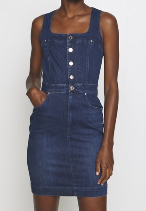 Denim-mekko tummansinisessä värissä, jossa on neliömainen pääntie, etupainike kiinnitys ja sivutaskut. Sujuva tekstuuri ja vartaloa myötäilevä muotoilu.