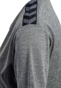 Grå långärmad tröja med texturerat tyg, med svart accentpanel på axeln och mönstrad detaljering på infodringen.