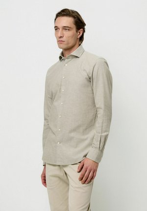 Lys beige langærmet skjorte lavet af tekstureret stof, med knaplukning foran og klassisk krave. Enkel design med bløde, neutrale farver.