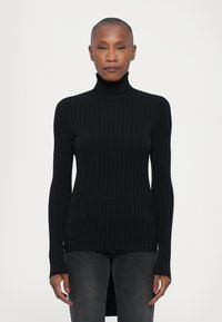 Svart ribbestrikket turtleneck genser med lange ermer, sidesplitt og en tettsittende design, laget av et glatt og elastisk stoff.