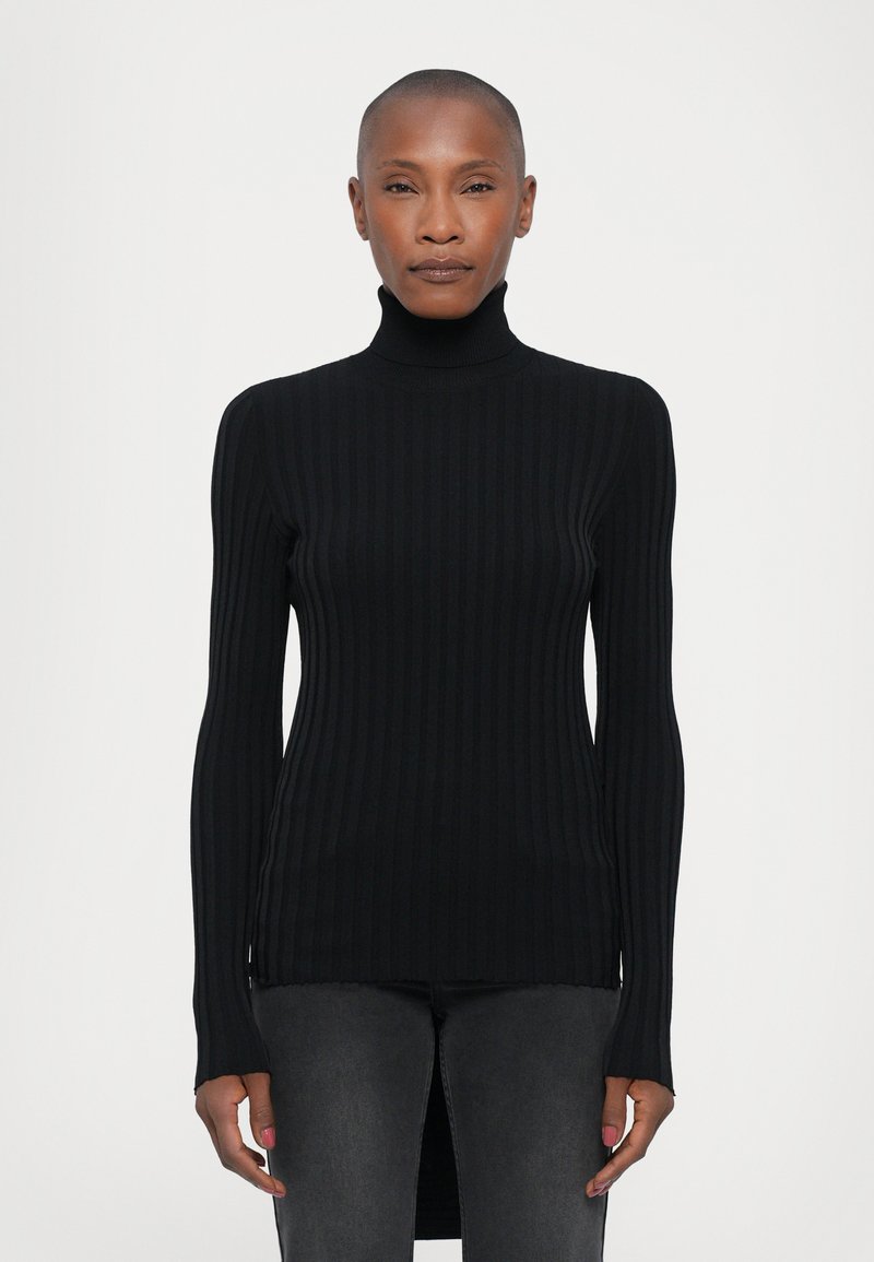 Svart ribbestrikket turtleneck genser med lange ermer, sidesplitt og en tettsittende design, laget av et glatt og elastisk stoff.