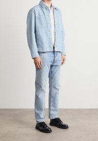 Light blue checkered denim jacket with long sleeves, paired with light blue jeans and black lace-up shoes. Flat texture with metal buttons.