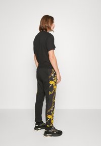 Versace Jeans Couture CHAIN - Trainingsbroek - black/gold