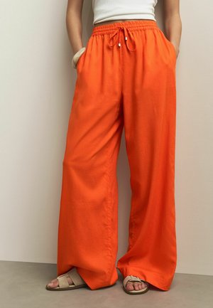 Orange wide-leg pants with an elastic waistband and drawstring. Made of lightweight fabric, featuring side pockets and a smooth texture.