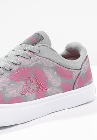 Sneaker in tela grigia con motivo a foglie rosa, superficie testurizzata, lacci grigi e suola in gomma bianca. Logo Kappa in rosa sul lato.