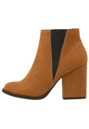 Dames enkellaars in bruin suède met blokhak en zwarte elastische zijkant, schuine neus en zwarte zool.