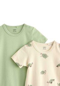 Deux t-shirts pour bébé : l'un en coton vert clair, l'autre beigne avec un motif de tortue. Tous deux ont des encolures rondes et des manches courtes.