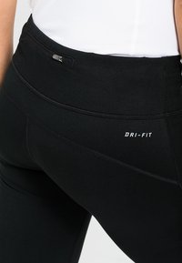 Czarne legginsy Dri-FIT o eleganckim designie, elastycznym materiale oraz bezpiecznej tylnej kieszeni z zamkiem błyskawicznym, zapewniające wygodę i funkcjonalność.