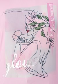 Pink shirt featuring a minimalist line drawing of a woman with flowers. Includes silver text reading "glow" and "Believe In Yourself."