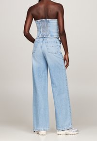 Ljusblå denimbyxor med vida ben och dragkedja, med en bakficka och en smockad överdel. Mjuk textur, avslappnad passform.