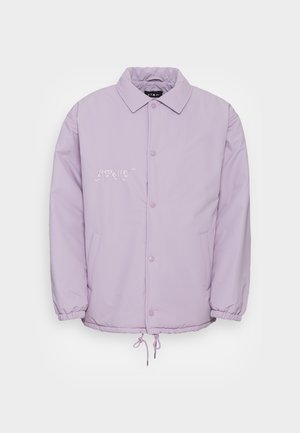Veste violet clair avec une fermeture à boutons-pression à l'avant, des poches latérales, des poignets élastiqués et un ourlet à cordon de serrage. Présente un logo "GRMY" brodé.