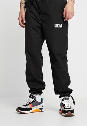 Pantalons de jogging noirs avec un waistband élastique et un détail de logo. Associés à des baskets multicolores avec un mélange de textures et de couleurs.