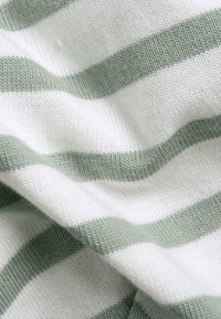 Gebreide stof in witte en zachte groene strepen, met een gestructureerd patroon waarin zichtbare stiksels en plooien zijn verwerkt, wat een gevoel van zachtheid en warmte suggereert.