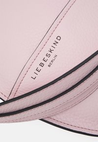 Borsa in pelle rosa pallido con rifiniture nere, caratterizzata da una superficie testurizzata e dal logo embossato "LIEBESKIND BERLIN", che mostra un design elegante.
