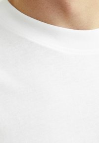 Hvid bomulds t-shirt med rund halsudskæring og ribbet kant, samt en glat, ensartet tekstur, set fra en tættere vinkel.