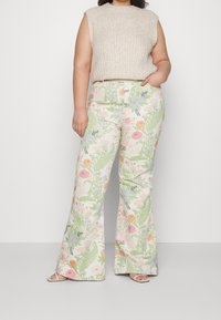 Pantalones acampanados con estampado floral en colores pastel sobre una base crema, con un patrón variado de flores y hojas. Combinados con un top de punto beige.