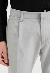 Světlé šedé kalhoty z texturované látky, s plochým předním dílem, pečlivým šitím a pasem s poutky na opasek.