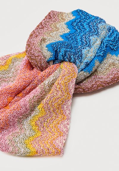 Πολύχρωμο πλεκτό ύφασμα με κυματιστά σχέδια σε μπλε, ροζ, κίτρινο και μπεζ, χαλαρά στριμμένο σε απλό φόντο.