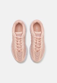 Ljust rosa träningsskor med mesh-ovandel, vadderad krage och snörning framtill. Har en texturerad design och en klar vit sula.