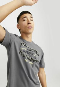 Grijze katoenen t-shirt met zwart en goud bedrukte tekst aan de voorkant. Korte mouwen, ronde halslijn en een relaxte pasvorm.
