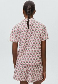 Set de pijama cu mânecă scurtă dintr-un material ușor, prezentând un model floral roz, cu pantaloni scurți asortați și o croială lejeră. Design texturat și respirabil.