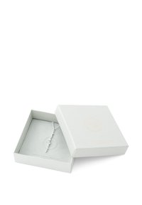 Sølv halskæde vist i en lysegrå boks med en tekstureret overflade, der har cirkulære accenter på en delikat kæde.