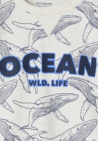 Gray sweatshirt featuring blue text that reads "OCEAN WLD. LIFE," with a repeated whale line drawing pattern. Fabric is soft, with ribbed neckline.