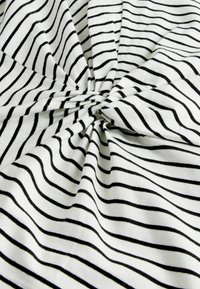 Kokvilnas audums ar vārpstveida dizainu, kurā attēlotas horizontālas melnas svītras uz baltā fona. Mīksta tekstūra ar vieglu spīdumu.