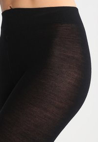 Sorte leggings lavet af et strækbart, gennemsigtigt materiale. Har en bred, ribbet linning og en glat tekstur hele vejen igennem.