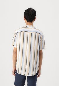 Camisa de manga corta con rayas verticales en beige, azul claro y negro. Confeccionada en tejido ligero, con un corte relajado y dobladillo curvado.