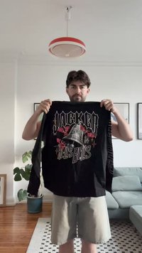 Juodas ilgomis rankovėmis grafikos marškinėliai su tekstu "JACKER HELL'S BELLS" ir varpo dizainu, su ryškiomis baltomis ir raudonomis akcentais.