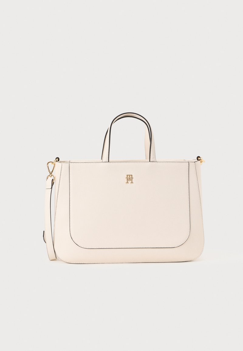 Sac à main beige clair avec une forme structurée. Doté de quincaillerie dorée, d'une bordure noire contrastante et de deux anses, ainsi qu'une bandoulière amovible.