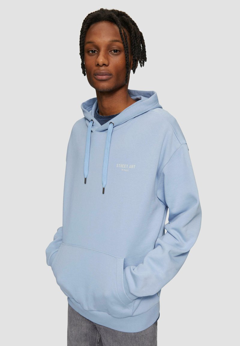 Lichtblauwe hoodie met een voorzak, aantrekkoord en "STREET ART" in het wit gedrukt. Zachte stof en een ontspannen pasvorm.