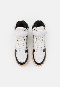 Högsko sneaker med ovandel i vitt läder, svarta lackläderdetaljer och en strukturerad svart foder. Har snören och justerbart rem.