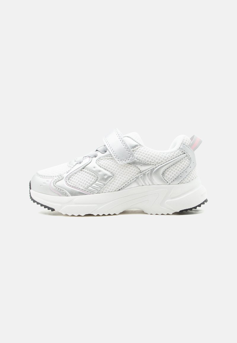 Λευκό αθλητικό sneaker με διχτυωτές επιφάνειες, λουράκι με ταινία Velcro, παχιά σόλα και μαύρο πέλμα σε ουδέτερο φόντο, πλευρική όψη.