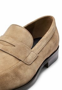 Lichtbruine suede instapper met een ronde neus en een slip-on ontwerp. Beschikt over een enkele band met een uitsnijdetail en een lage houten hak.