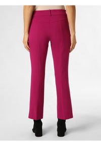 Fuksjowe spodnie o dopasowanym kroju z wysokim stanem i rozszerzanym nogawkiem, wykonane z gładkiego materiału, połączone z czarnymi botkami na obcasie.