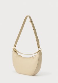 Μπεζ δερμάτινη τσάντα ώμου με καμπυλωτό σχήμα, ρυθμιζόμενο λουρί και μεταλλικά στοιχεία σε χρυσό τόνο. Διαθέτει ομαλή υφή με ελάχιστες λεπτομέρειες.