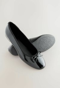 Schwarze Lackleder-Ballerinas mit runder Zehenpartie und kleiner Schleifendetail auf der Vorderseite. Texturierten Gummisohle mit Logomuster.