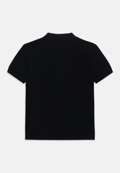 Μαύρο κοντομάνικο πόλο πουκάμισο που φαίνεται από πίσω, με διπλωμένο γιακά και απλό σχέδιο σε λευκό φόντο.