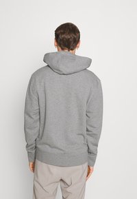 Grau Kapuzenpullover aus weichem Stoff. Hat eine lockere Passform, gerippte Bündchen und einen elastischen Saum. Einfaches Design ohne sichtbare Logos oder Muster.